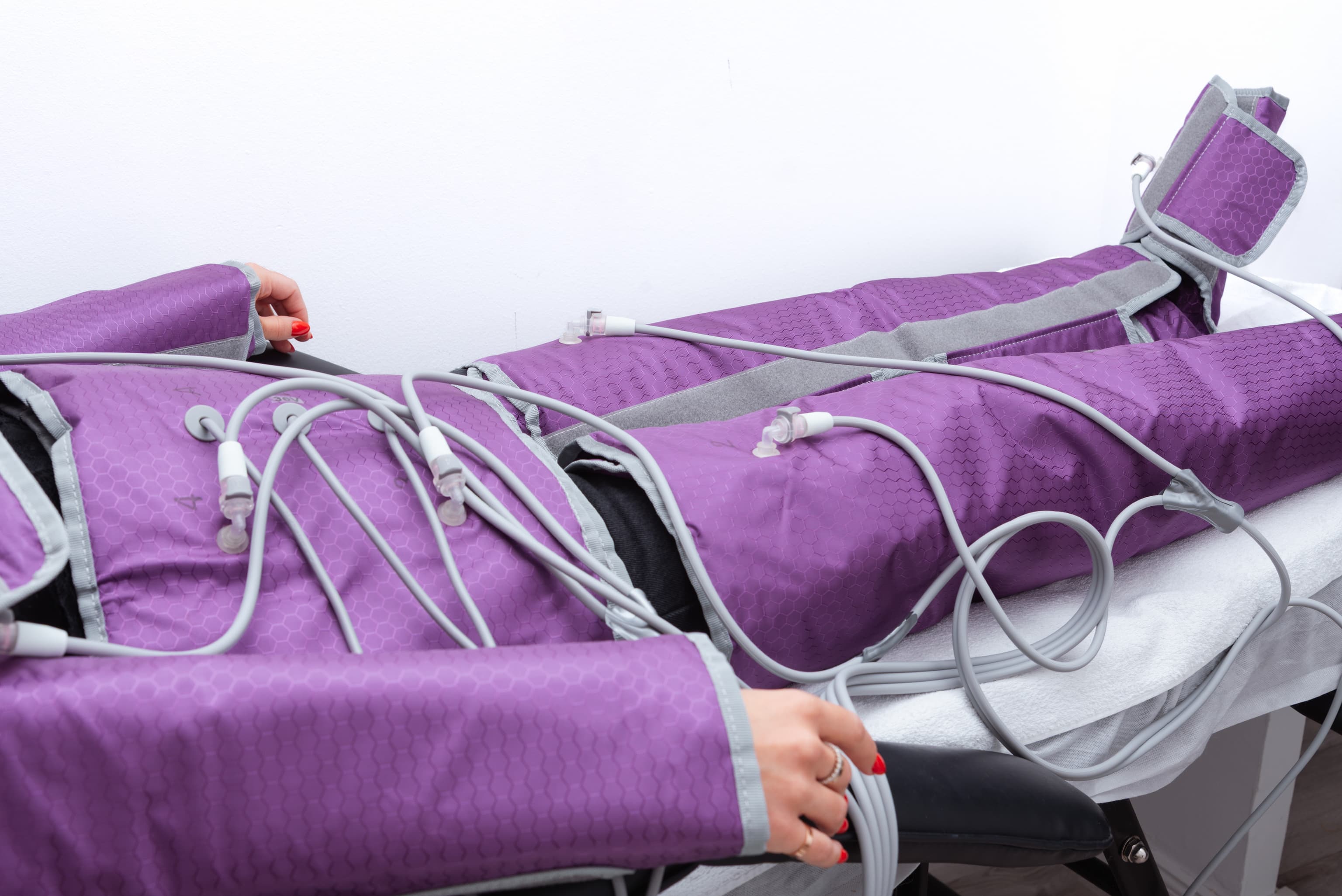 Nyomásterápiás ruha a kezelőágyon fekvő vendégen, csatlakoztatott géppel.